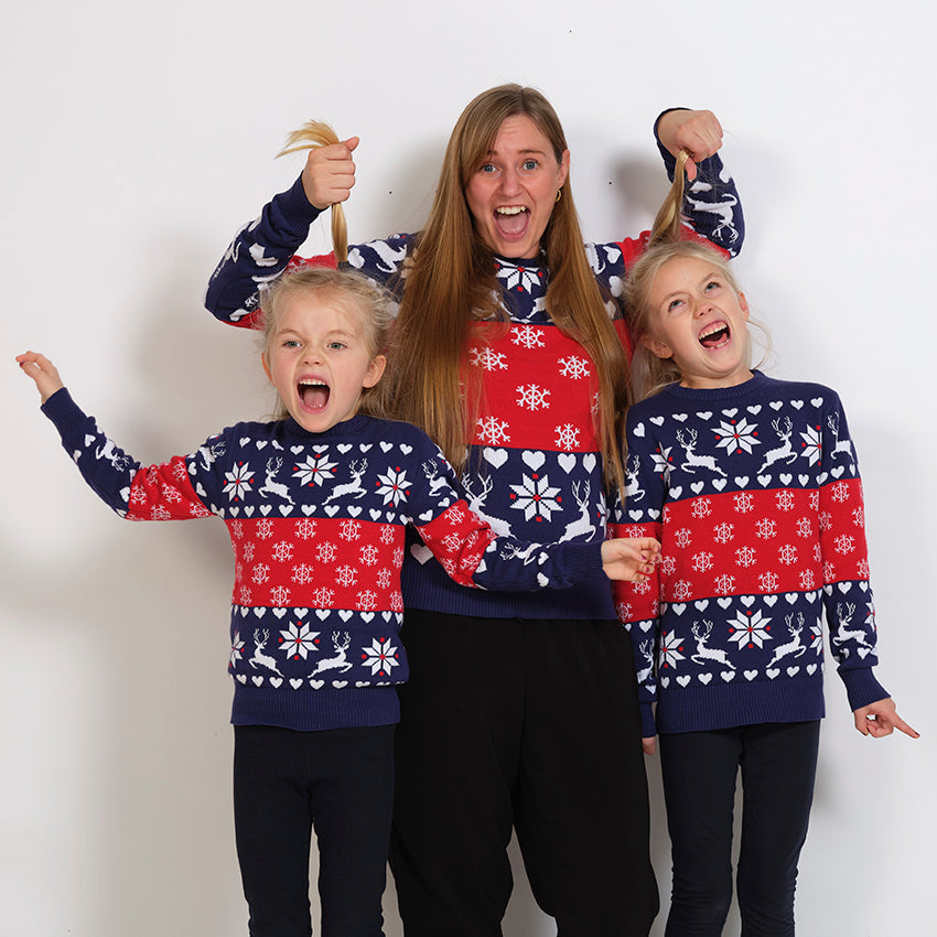 En familj i röd och blå jultröja med snöflingor och renar.